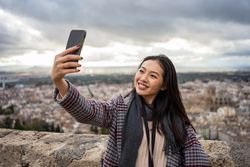 Asian tourist taking selfie against old city