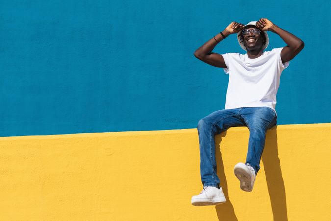Happy man sitting on colorful wall
