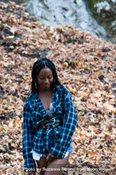 Young woman standing in front of fall leaves in fashionable outfit looking down 5Q2aX4