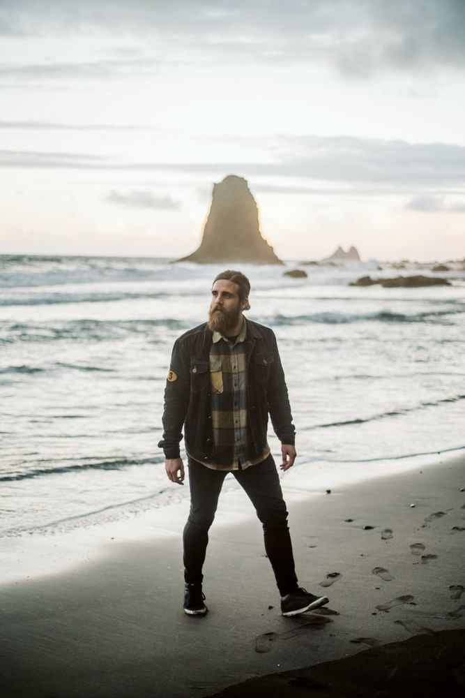 Bearded traveler looking away near sea