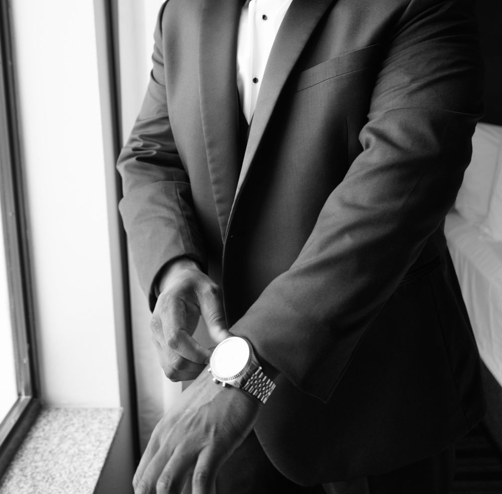 Grayscale photo of groom adjusting his sleeve and getting ready for wedding