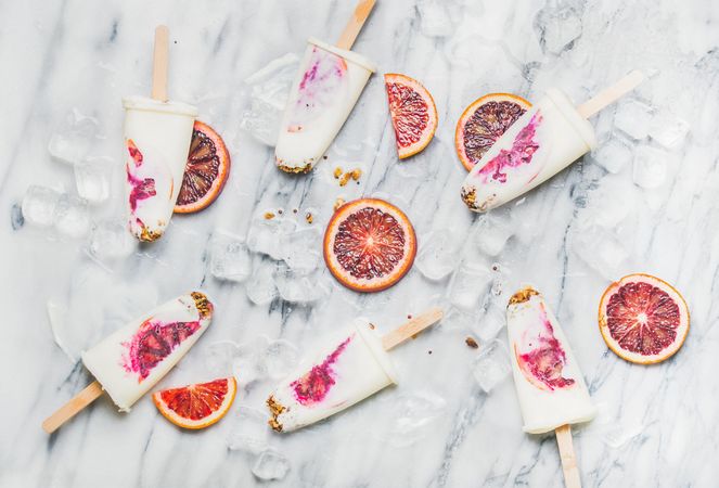 Blood orange home-made ice pops laying on marble