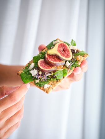 Crop person with delicious fruit slices on bread