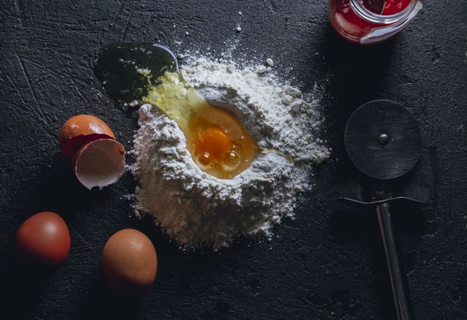 Broken egg and flour on dark background