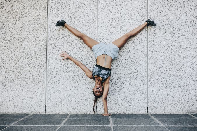 Acrobatic fitness woman balancing upside down on one hand with legs in air