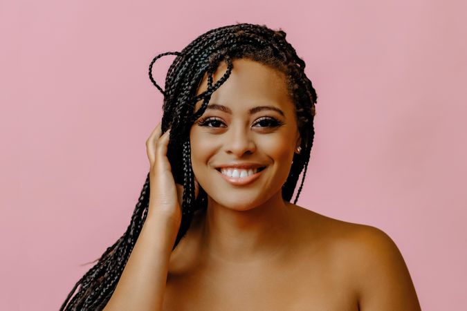 Happy female smiling and touching her hair in pink studio shoot