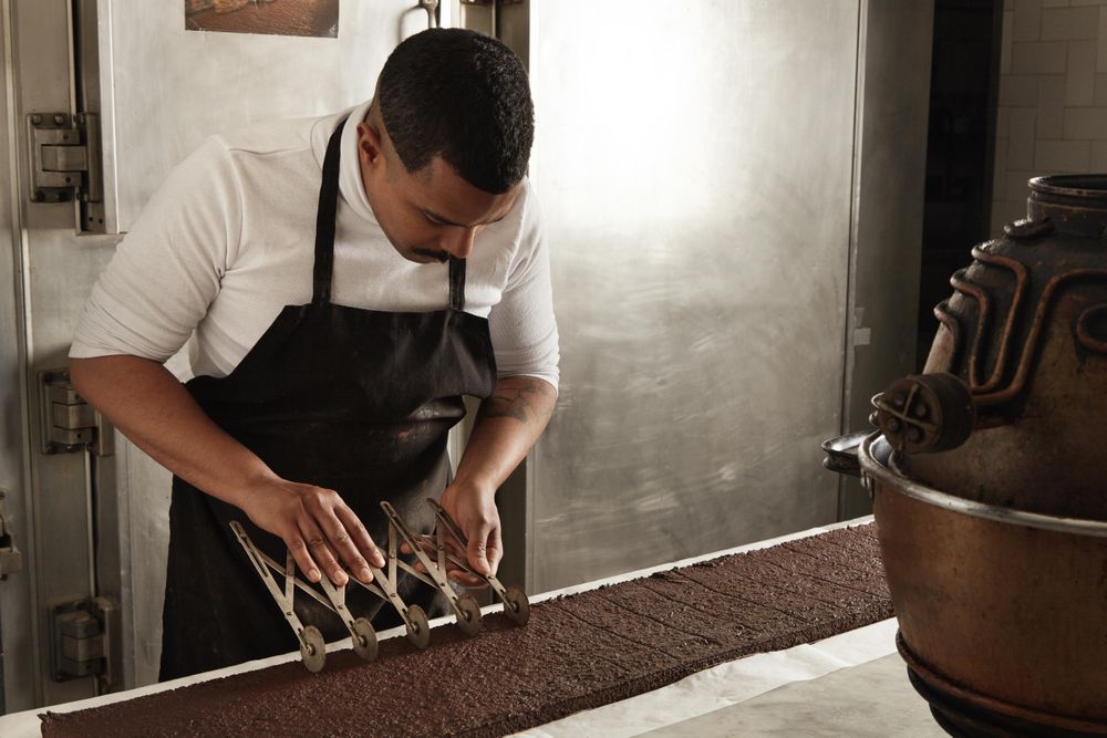 Man in apron working in professional kitchen cutting slices of cake