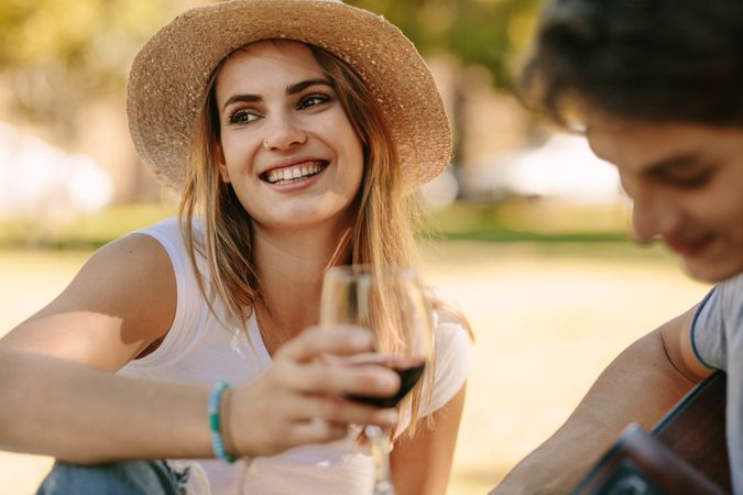 Close up of a woman sitting in park holding a wine glass