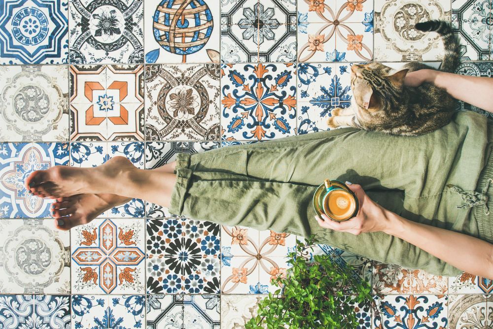 Woman on tiled terrace with coffee and cat
