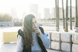 Young teenage girl sitting down and smoking outdoors