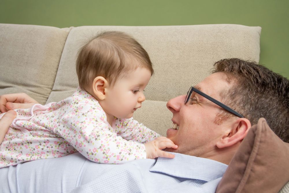 Baby lying on smiling father's chest