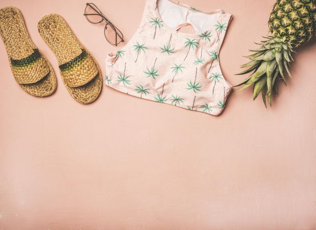 Sandals, glasses, bikini top, pineapple on pink background, with copy space