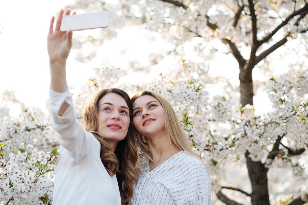 Friends taking selfie near blooming trees