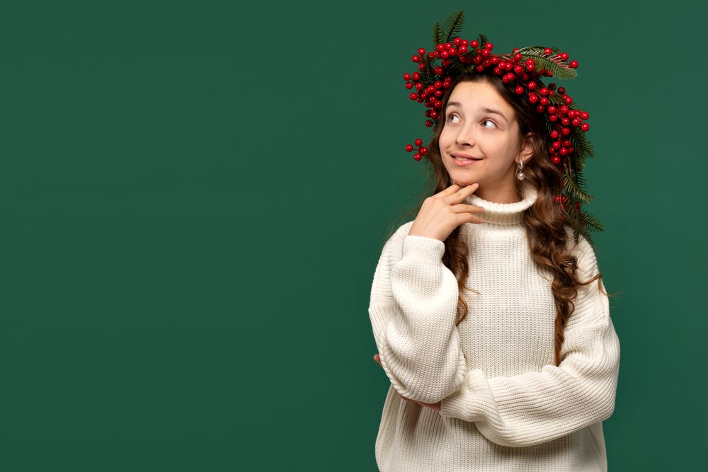 Smiling girl in festive red berry wreath looking thoughtfully.