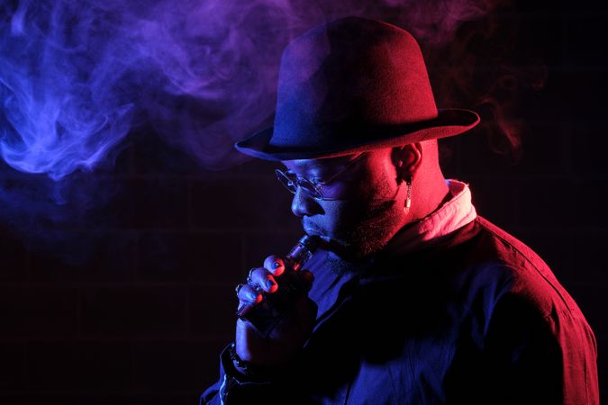 Bearded man smoking vape in dark room