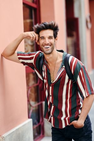 Smiling man with dark hair and modern hairstyle wearing casual clothes outdoors