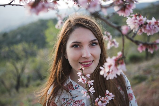 Young happy woman between trees in garden