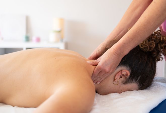 Masseuse massaging neck of woman in spa salon