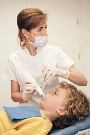 Woman scanning teeth of boy in medical office