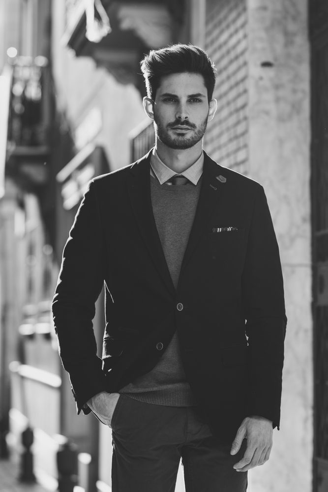 Serious man in the street wearing elegant suit with sun in background, b&w