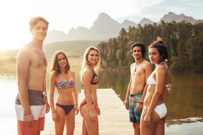 Portrait of young people in swimwear standing by a lake and looking at camera