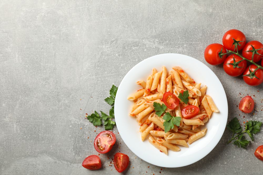 Composition with plate of tasty pasta on gray background, top view