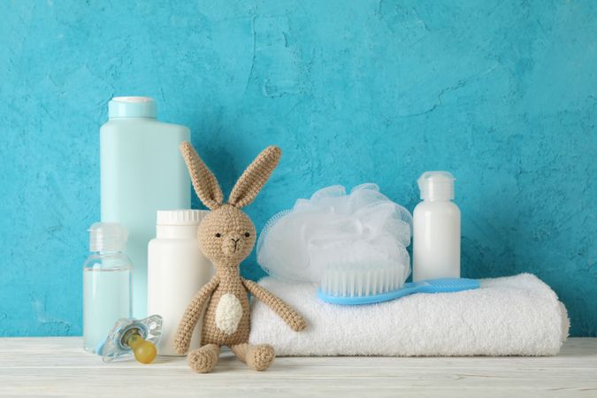 Baby hygiene accessories on wooden table against blue background