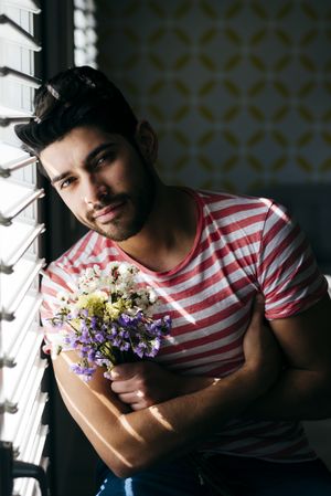 Young confident man with flowers looking at camera