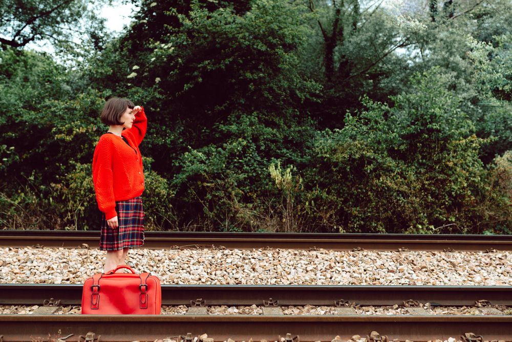 Woman with suitcase walking on railroad ties