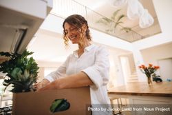 Smiling woman looking in the box of groceries in her kitchen 4mmGe4