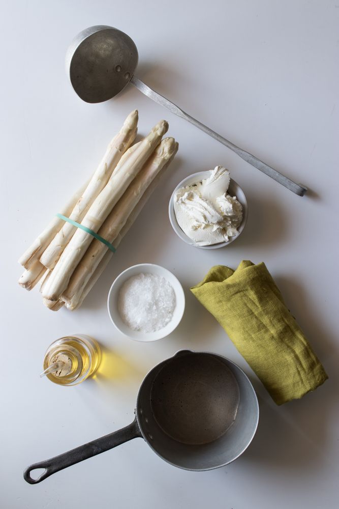 Asparagus and cream amidst kitchenware and condiments