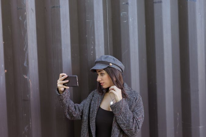 Charming Hispanic lady taking selfie near wall