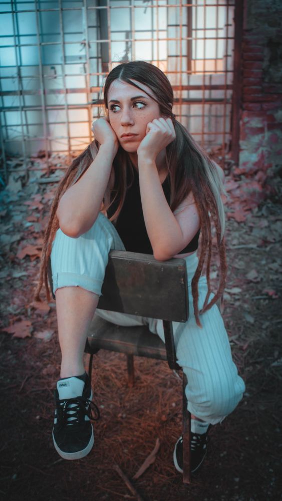 Sad woman in blue pant sitting on chair outdoor