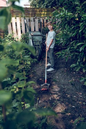 Kid standing in garden with cultivator