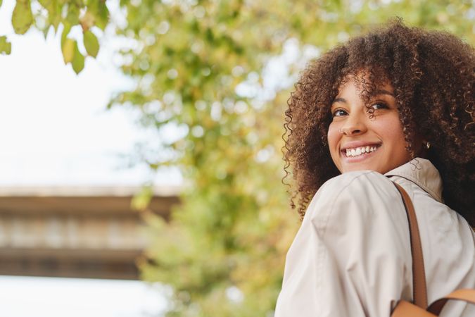 Smiling Black woman with curly hair in park