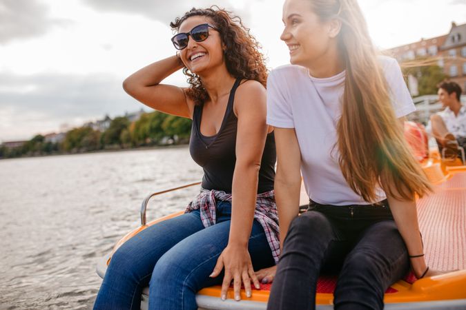 Outdoors shot of two female friends sitting in front pedal boat