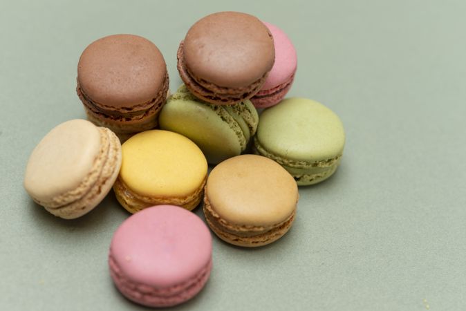 Looking down at macaroons scattered on a green table with copy space