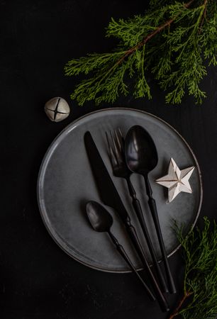 Dark cutlery on dark plate with star and bell ornament