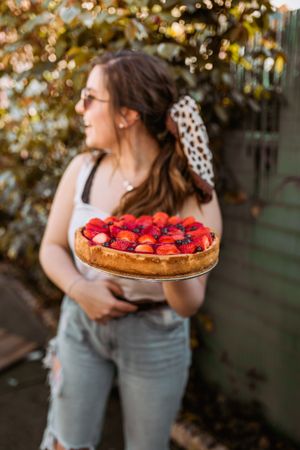 cheerful woman holding a delicious strawberry pie