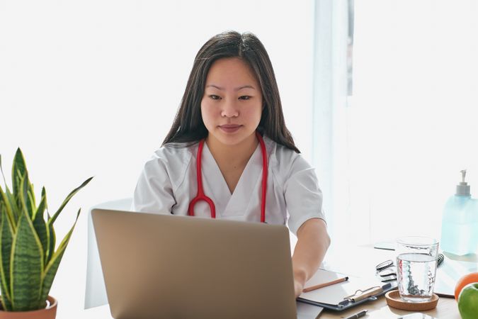 Asian doctor working on laptop in modern clinic