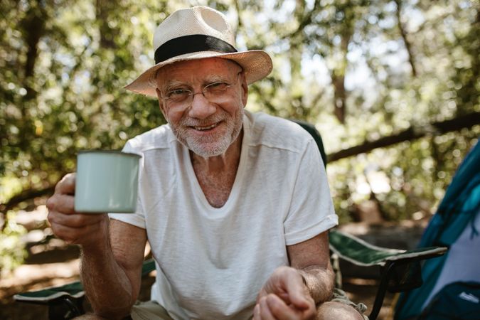 Smiling older man having refreshing coffee at campsite