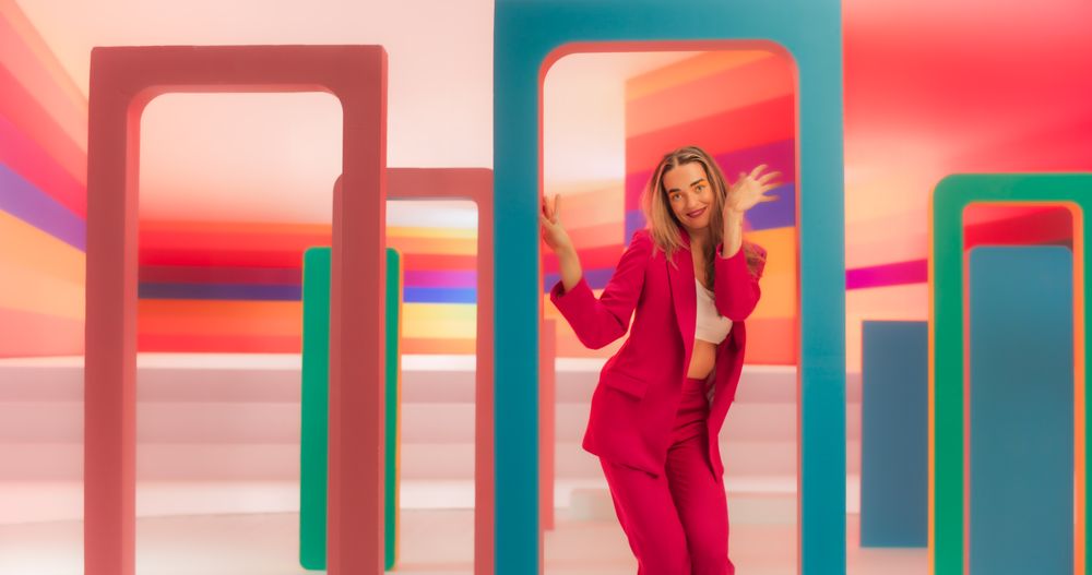 Portrait of Professional Dancer Performing a Routine in Front of a Big Digital Led Wall Screen with Colorful Background in Studio Environment. She is Interacting with Geometric Decoration Prop On Set