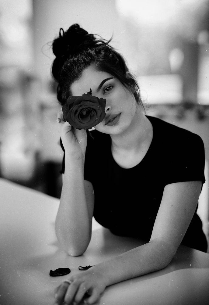 Grayscale photo of woman holding rose to her eyes