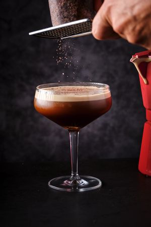 Unrecognizable bartender grating chocolate in cocktail