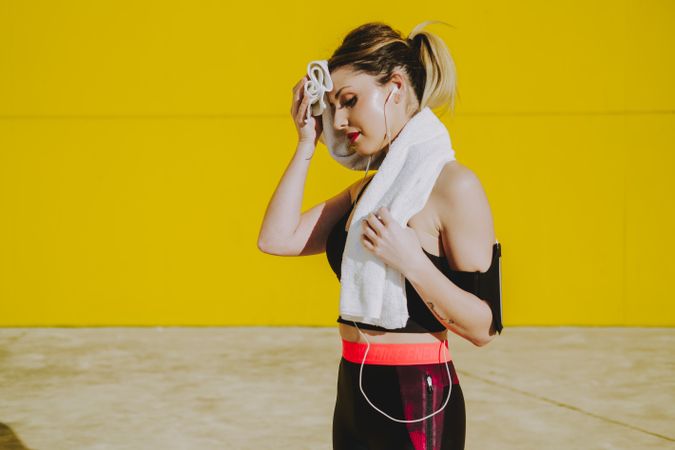 Woman cleaning with sweat towel on yellow background