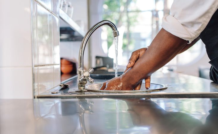 Close up of chef washing his hands in commercial kitchen
