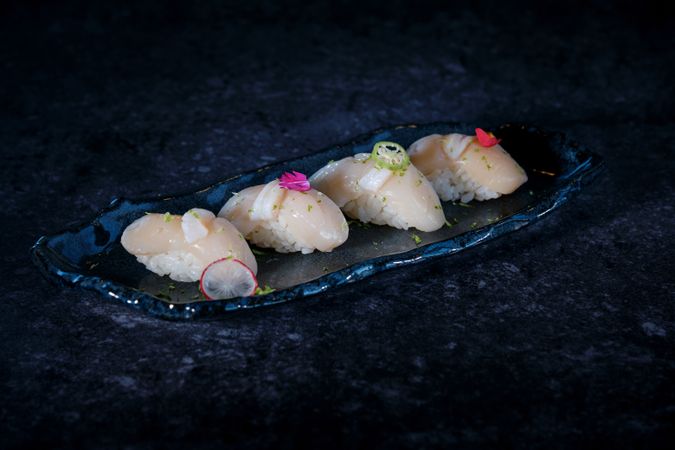 Delicious nigiri sushi with flowers on marble plate