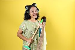 Asian Woman in Hair Rolls Holding Cleaning Tools.