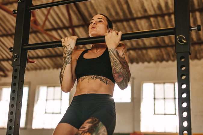 Female doing pull up workout in empty factory shade