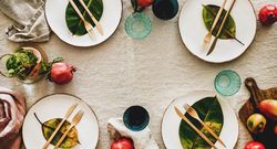 Fresh table setting on brown table cloth, leaves on bright plates, fruit, wide composition